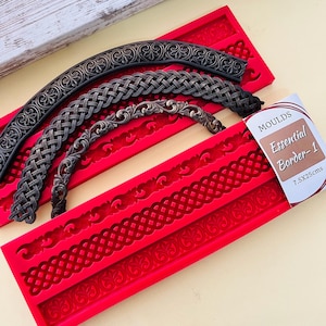 May include: A bright red silicone mold for crafting borders, featuring three distinct decorative patterns. The mold includes a label reading MOULDS Essential Border-1 7.5X25cms. Three dark metallic curved decorative strips are placed on top.