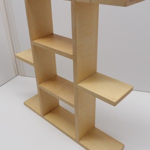 Puede incluir: Una estanter&iacute;a de pared de madera clara con cuatro estantes. La estanter&iacute;a est&aacute; hecha de madera sin tratar y tiene un dise&ntilde;o sencillo.