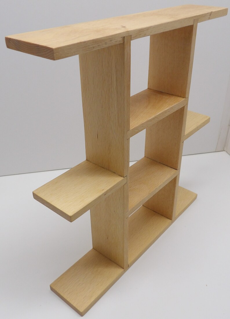 Puede incluir: Una estanter&iacute;a de madera clara con cinco estantes, cada uno de diferente tama&ntilde;o y forma. Los estantes est&aacute;n dispuestos en forma escalonada, creando un dise&ntilde;o &uacute;nico y moderno.