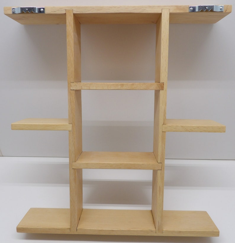 Puede incluir: Una estanter&iacute;a de pared de madera clara con cuatro estantes. La estanter&iacute;a est&aacute; fijada a la pared con dos soportes met&aacute;licos.