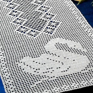 Può includere: Un runner da tavolo in crochet bianco con un motivo floreale. Il runner è realizzato con delicati punti a crochet e presenta un motivo floreale ripetitivo.