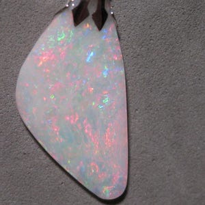 May include: A pear-shaped pendant with a white opal stone. The opal displays a play of color with pink, green, and blue hues. The pendant has a silver-colored metal top.