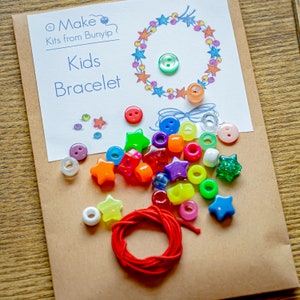 May include: A craft kit for making a kids bracelet. The kit includes colourful beads, star-shaped beads, buttons, and a red string. The kit comes with a card that says "Make Kits from Bunyip Kids Bracelet".