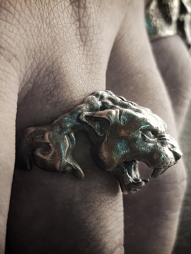 May include: A silver ring featuring a detailed sculpture of a snarling panther head.