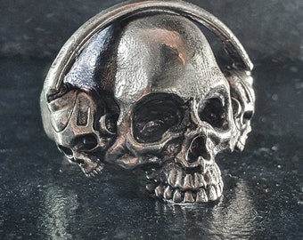 Könnte beinhalten: Ein silberner Totenkopfring mit einem detaillierten Design eines Totenkopfs, der Kopfhörer trägt. Der Ring ist ein Statement-Piece mit einem gotischen und kantigen Stil.