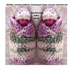 May include: A crochet pattern for a baby cocoon and hat set. The set is made in a pink, purple and grey colour scheme. The cocoon has buttons down the front and the hat is a simple beanie style.