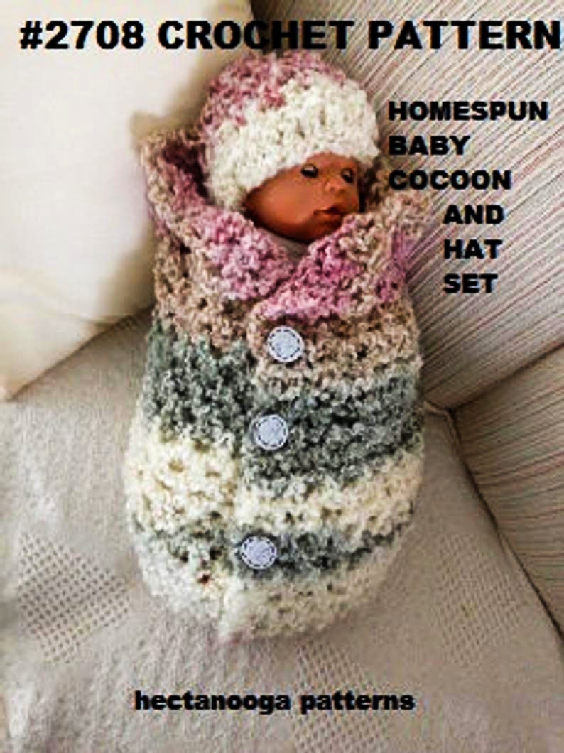 May include: A crocheted baby cocoon and hat set in pink, white, and grey. The set is made with a homespun yarn and features buttons.