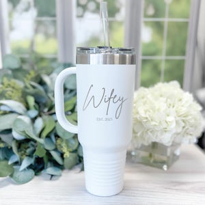 May include: White travel mug with a handle and a straw. The mug has the text "Wifey Est. 2025" printed on it.