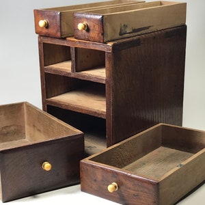 May include: A wooden box with multiple drawers and shelves. The box is made of dark wood and has brass knobs. The drawers are open and the shelves are empty.