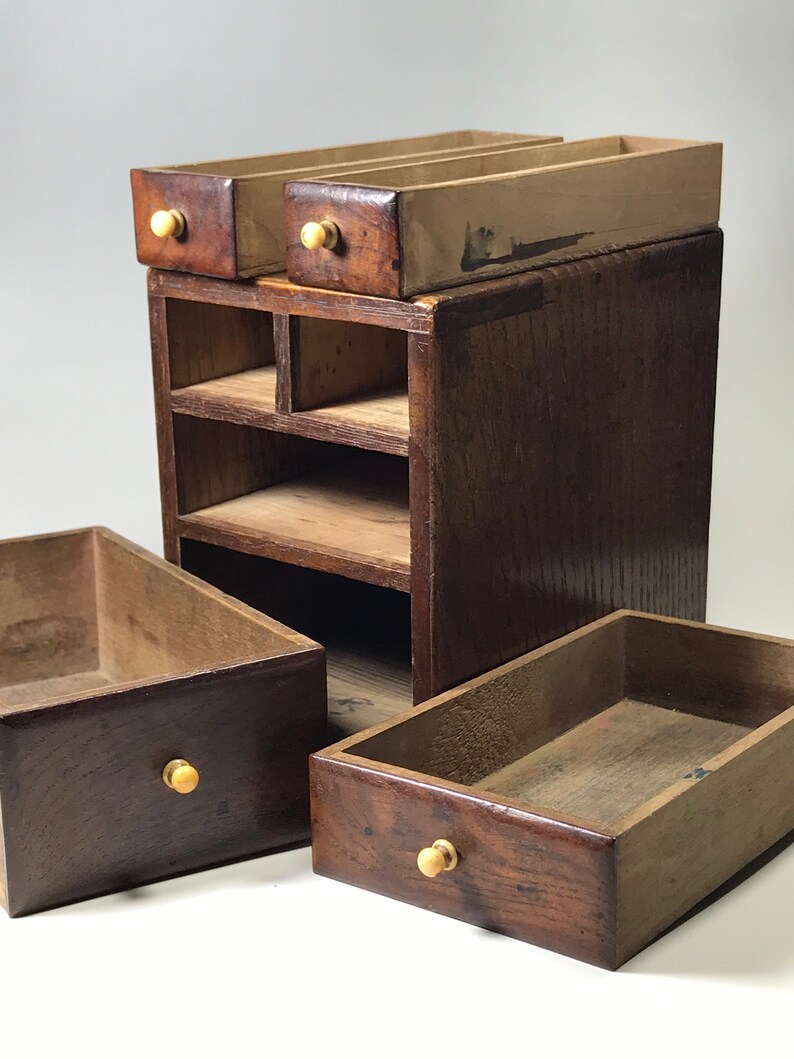 May include: A wooden box with multiple drawers and shelves. The box is made of dark wood and has brass knobs. The drawers are open and the shelves are empty.