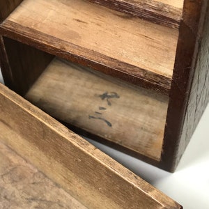 May include: A wooden box with multiple compartments, each with a separate lid. The box is made of dark brown wood and has a natural wood finish. The box is open and the inside is visible. The inside of the box is lined with a light brown wood. The box has a small inscription on the bottom of the box that reads "三".