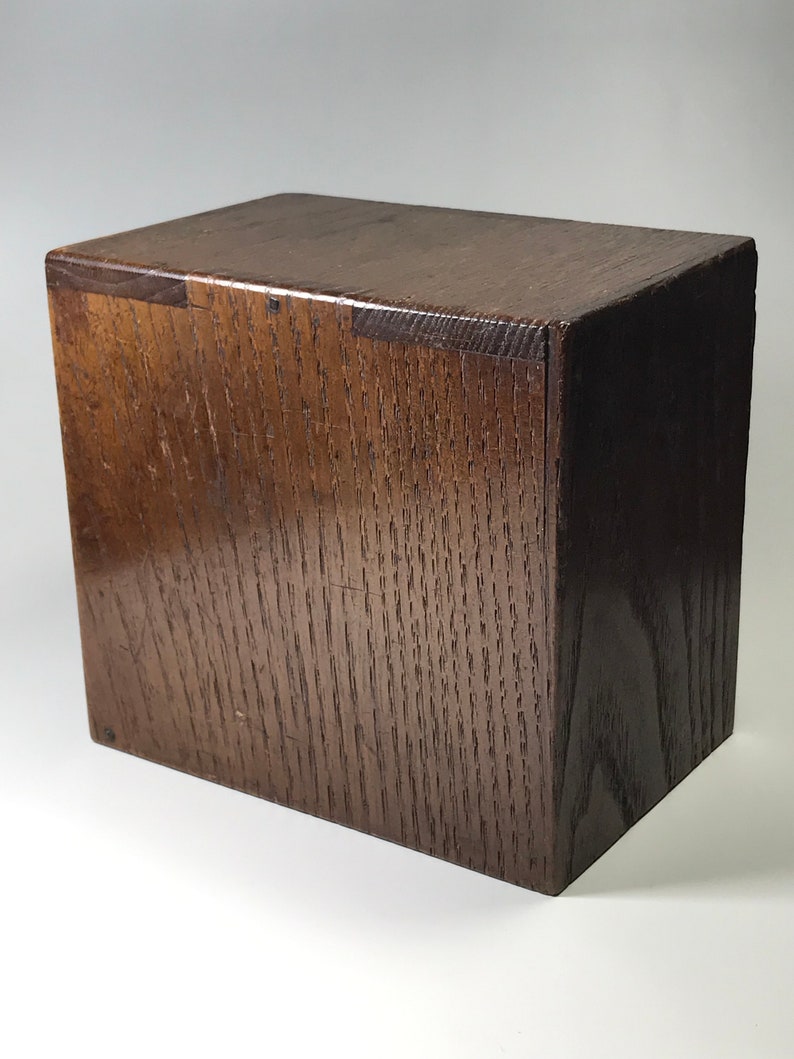 May include: A dark brown wooden box with a simple, rectangular design. The box is made of solid wood and has a smooth, polished finish.