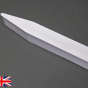 Puede incluir: Una etiqueta de planta de plástico blanco con un extremo puntiagudo. La etiqueta está en blanco y lista para escribir.