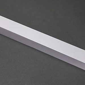 Puede incluir: Una pila de papel blanco, que se asemeja a un bloque rectangular largo.