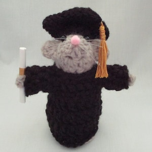 May include: A crocheted gray mouse wearing a black graduation cap and gown, holding a white scroll. The cap has a gold tassel.