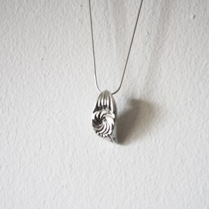May include: A silver necklace with a spiral-shaped pendant.