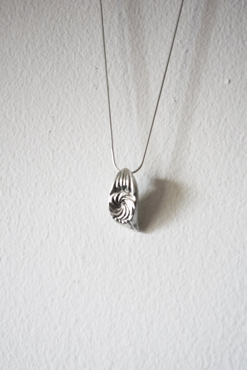 May include: A silver necklace with a spiral-shaped pendant.