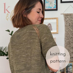 May include: An olive green knitted sweater with an open shoulder detail. The sweater has a round neckline and long sleeves. The words "knitting pattern" are displayed on a white circle in the lower right corner.