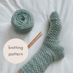 Può includere: Un calzino di lana verde con un motivo testurizzato, un gomitolo di lana verde e ferri da maglia in legno. L'immagine include il testo "knitting pattern".