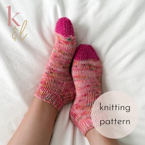 Può includere: Un paio di calzini lavorati a mano con un motivo maculato rosa e multicolore. Le dita e i polsini sono di un rosa acceso e uniforme. Il testo "knitting pattern" è in un cerchio bianco.