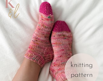 May include: A pair of hand-knitted socks with a pink and multicolored speckled pattern. The toes and cuffs are a solid, vibrant pink. The text "knitting pattern" is in a white circle.
