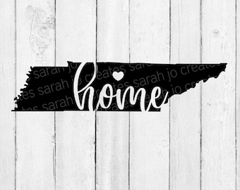 May include: Black silhouette of the state of Tennessee with the word "home" written in white cursive script with a small white heart above the word. The background is a white woodgrain pattern.