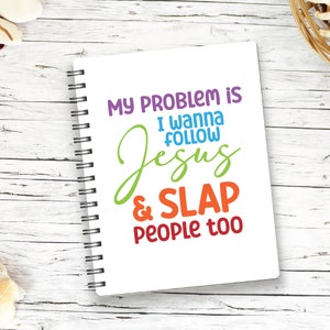 K&ouml;nnte beinhalten: Ein wei&szlig;es Notizbuch mit Spiralbindung und dem farbigen Aufdruck: MY PROBLEM IS I WANNA FOLLOW Jesus & SLAP PEOPLE too. Die W&ouml;rter sind in Lila, Blau, Gr&uuml;n, Orange und Rot gedruckt, mit einer schwarzen Metallspirale an der linken Seite.