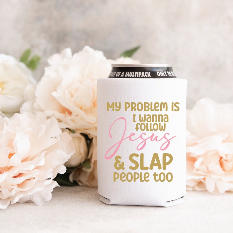 K&ouml;nnte beinhalten: Ein wei&szlig;er Dosenk&uuml;hler aus Schaumstoff mit dem goldenen und rosafarbenen Text "MY PROBLEM IS I WANNA FOLLOW Jesus & SLAP PEOPLE too". Der Dosenk&uuml;hler ist zylindrisch und passt um eine Standard-Getr&auml;nkedose mit einem sichtbaren schwarzen Rand.