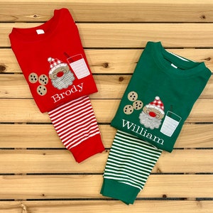May include: Two pairs of red and green pajamas with a Santa Claus design and personalized names "Brody" and "William".