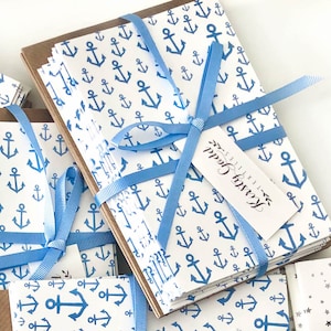 Puede incluir: Una pila de tarjetas blancas con un patrón de ancla azul, atadas con una cinta azul y una pequeña etiqueta blanca que dice "Kirsty Godd Textiles".