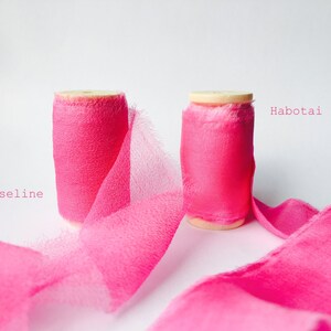 May include: Two spools of pink ribbon, one labeled "Habotai" and the other labeled "Mouseline".