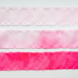 May include: Three strips of fabric, each with a different shade of pink. The top strip is the lightest shade of pink, the middle strip is a medium shade of pink, and the bottom strip is the darkest shade of pink.