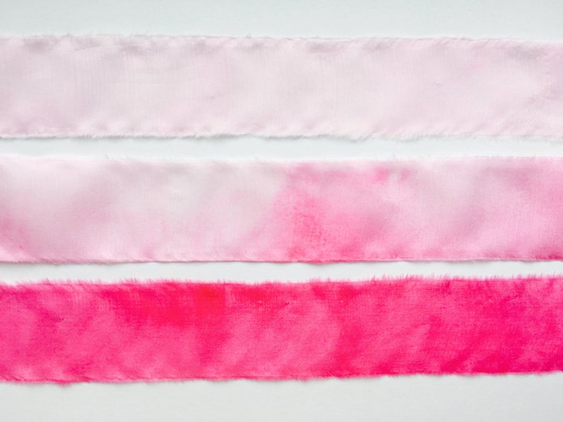 May include: Three strips of fabric, each with a different shade of pink. The top strip is the lightest shade of pink, the middle strip is a medium shade of pink, and the bottom strip is the darkest shade of pink.