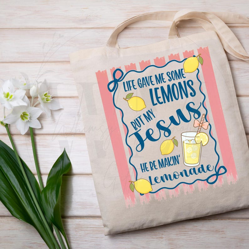 K&ouml;nnte beinhalten: Beige Tragetasche mit rosa und blauem Design. Das Design enth&auml;lt den Text "Life gave me some lemons but my Jesus he be makin' lemonade" mit Illustrationen von Zitronen und einem Glas Limonade.