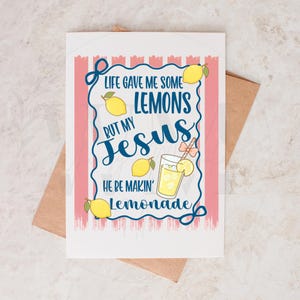 K&ouml;nnte beinhalten: Eine wei&szlig;e Gru&szlig;karte mit einem rosa-wei&szlig; gestreiften Rand und dem Text "Life gave me some lemons but my Jesus he be makin' lemonade." Die Karte zeigt Illustrationen von Zitronen und einem Glas Limonade. Ein brauner Umschlag befindet sich hinter der Karte.