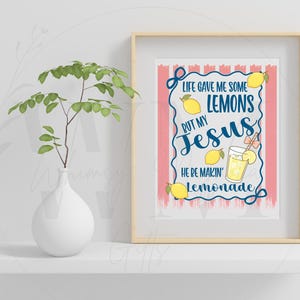 K&ouml;nnte beinhalten: Gerahmter Druck mit dem Text "Life gave me some lemons but my Jesus he's makin' lemonade". Der Druck zeigt Zitronen und ein Glas Limonade. Eine wei&szlig;e Vase mit einer gr&uuml;nen Pflanze steht auf einem wei&szlig;en Regal.