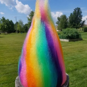 May include: A rainbow-colored yarn ball with a fluffy texture. The yarn is arranged in vertical stripes of pink, orange, yellow, green, blue, and purple.