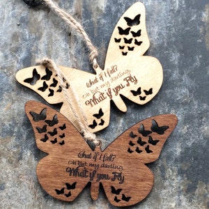 May include: Two wooden butterfly ornaments with a cutout design. The butterflies are painted in shades of brown and have the text "What if I fall? Oh but my darling, What if you fly" engraved on them.