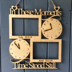Puede incluir: Adorno de pared de madera con dos marcos de fotos y dos relojes. Los textos "In These Moments" y "Time Stood Still" están recortados. También se incluyen los nombres Lyla y Avaé con fechas.