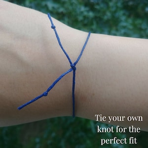 This shows an example on how you tie the bracelet on your wrist. You tie your own knot for the perfect fit. You can then cut any excess cord. The cord in this example is navy blue.