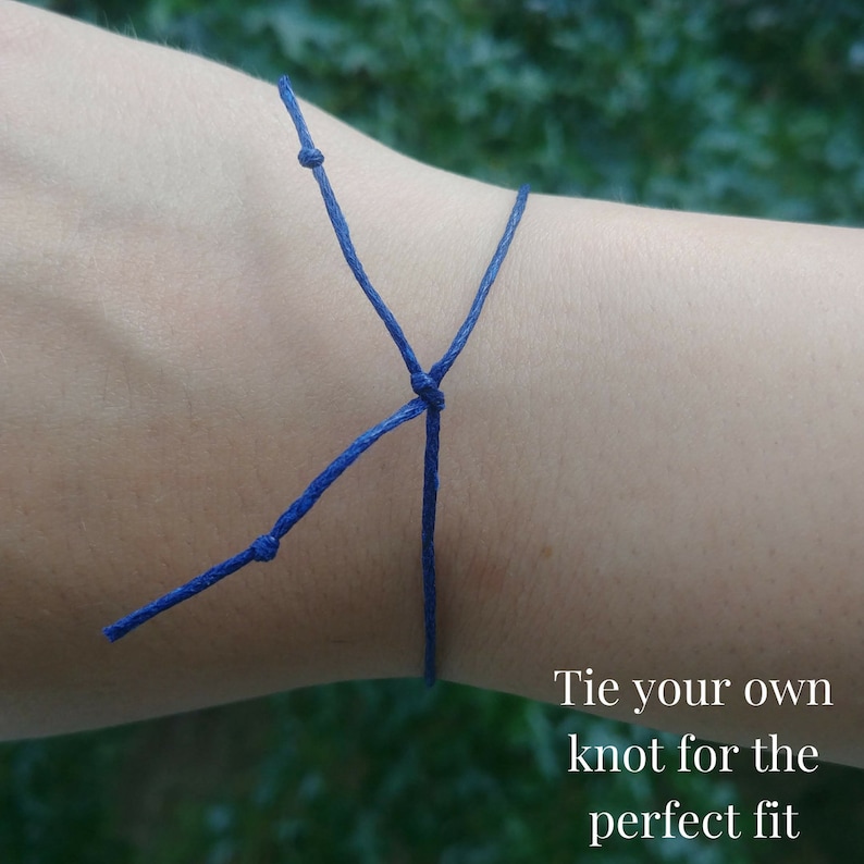 This shows an example on how you tie the bracelet on your wrist. You tie your own knot for the perfect fit. You can then cut any excess cord. The cord in this example is navy blue.