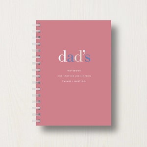 May include: A pink notebook with the text "dad's" in blue and white. The notebook says "Notebook" and "Christopher Joe Simpson" and "Things I Must Do!" in white text.