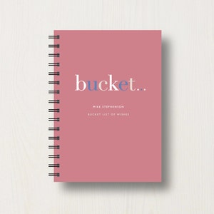 May include: A pink spiral bound notebook with the word "bucket..." in blue and white text. The text "Mike Stephenson" and "Bucket List of Wishes" is printed in white below the title.