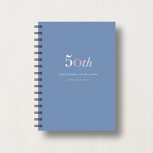 May include: A blue spiral bound notebook with the text "50th" in white with a pink "o". The text "Christopher Joe Williams" and "15th July 2017" is printed below the number.