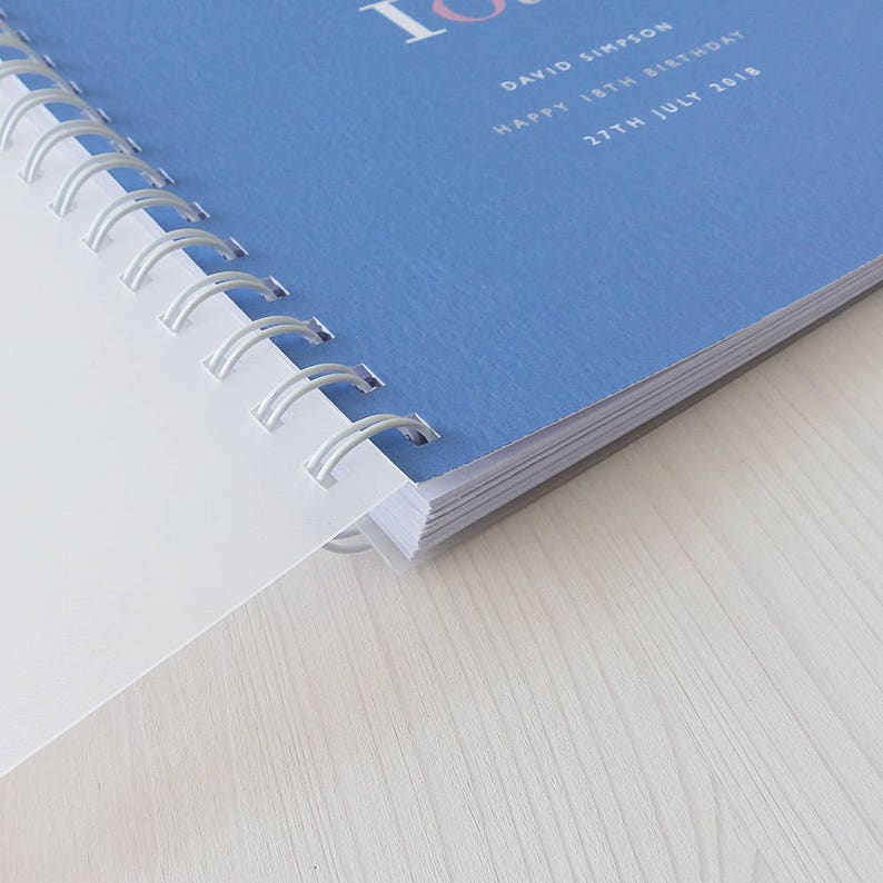 May include: A blue spiral bound notebook with the text "David Simpson Happy 18th Birthday 27th July 2018" printed on the cover.