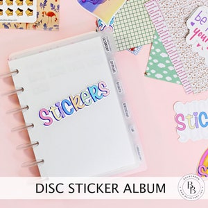 Könnte beinhalten: Ein weißes Stickeralbum mit Scheibenbindung und transparenten Trennwänden mit den Aufschriften "Aktivitäten", "Tiere", "Schönheit", "Geburtstage", "Café" und "Feier". Auf dem Cover befindet sich ein farbenfroher "Stickers"-Aufkleber. Das Album liegt auf einer rosa Oberfläche.