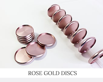 May include: Rose gold metal discs, arranged in stacks and rows, with a shiny, metallic finish. The discs are round with a flat surface and a slightly raised edge. The text "ROSE GOLD DISCS" is displayed below the discs.