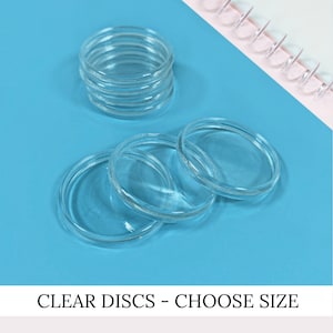 May include: A set of clear glass discs of various sizes. The discs are stacked on top of each other and are arranged on a blue surface. CLEAR DISCS - CHOOSE SIZE is written in white text on a black background.