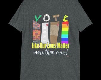 May include: A dark heather grey t-shirt with a graphic design featuring the word "VOTE" in colorful letters. The letters are made up of different patterns and textures, including a rainbow, a brown fabric, and a patterned fabric. The text "Like Our Lives Matter more than ever!" is printed below the graphic.