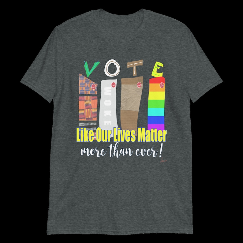 May include: A dark heather grey t-shirt with a graphic design featuring the word "VOTE" in colorful letters. The letters are made up of different patterns and textures, including a rainbow, a brown fabric, and a patterned fabric. The text "Like Our Lives Matter more than ever!" is printed below the graphic.